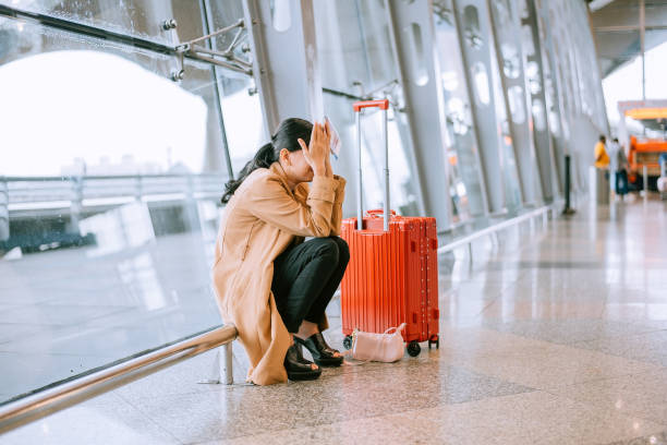 Frustrated male traveler with luggage waiting in airport terminal during flight delay